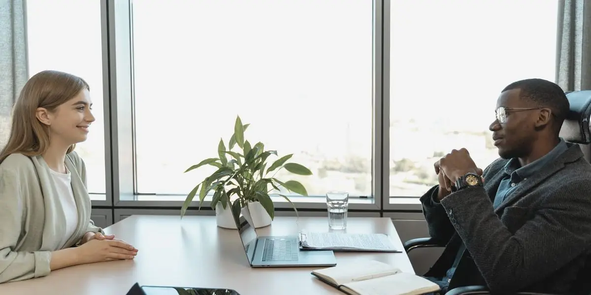 Bewerberin und Gesprächspartner im Vorstellungsgespräch an einem hellen Bürotisch
